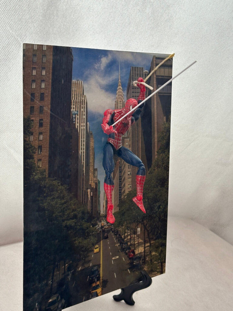 Superhero edition collectable figure and display (web slinger), custom background. Includes stand and wall attachment